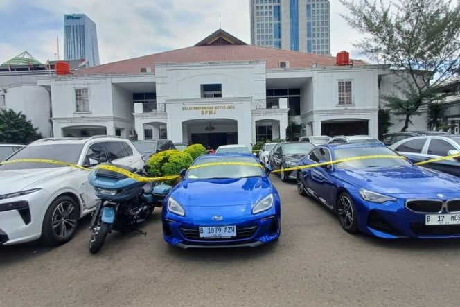
					Sejumlah mobil dan sepeda motor disita terkait kasus pegawai Kementerian Komunikasi dan Digital (Komdigi) melindungi ribuan situs judi online (judol). (KOMPAS.com/BAHARUDIN AL FARISI )